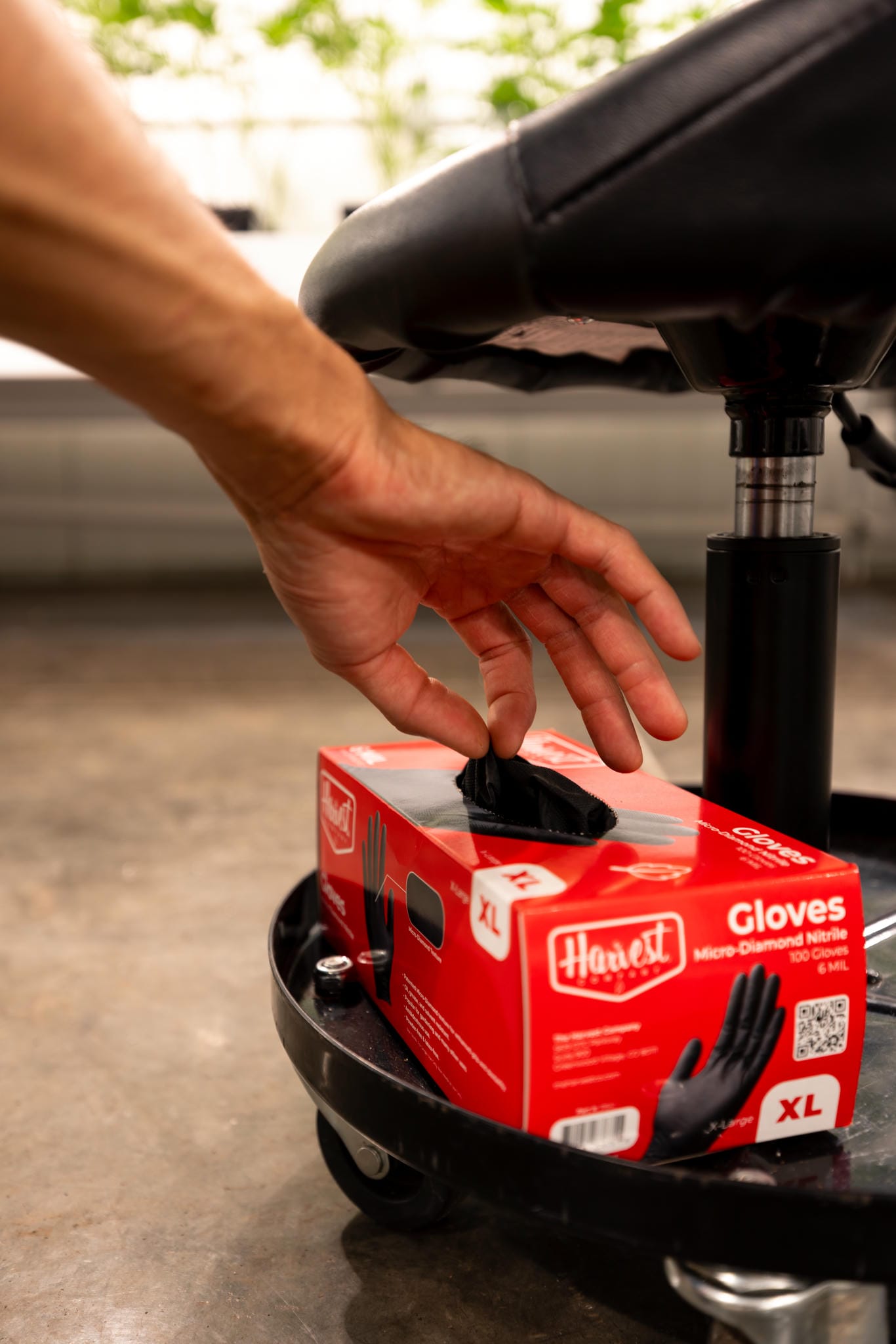 Hand reaching for a box of gloves on a black surface with blurred background