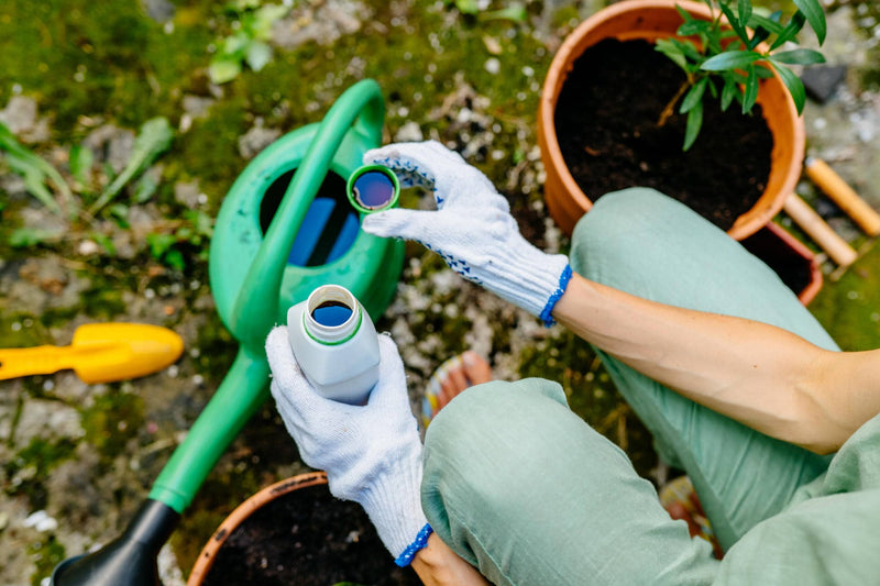Two hands treating common plant diseases in backyard mixing product above a watering can