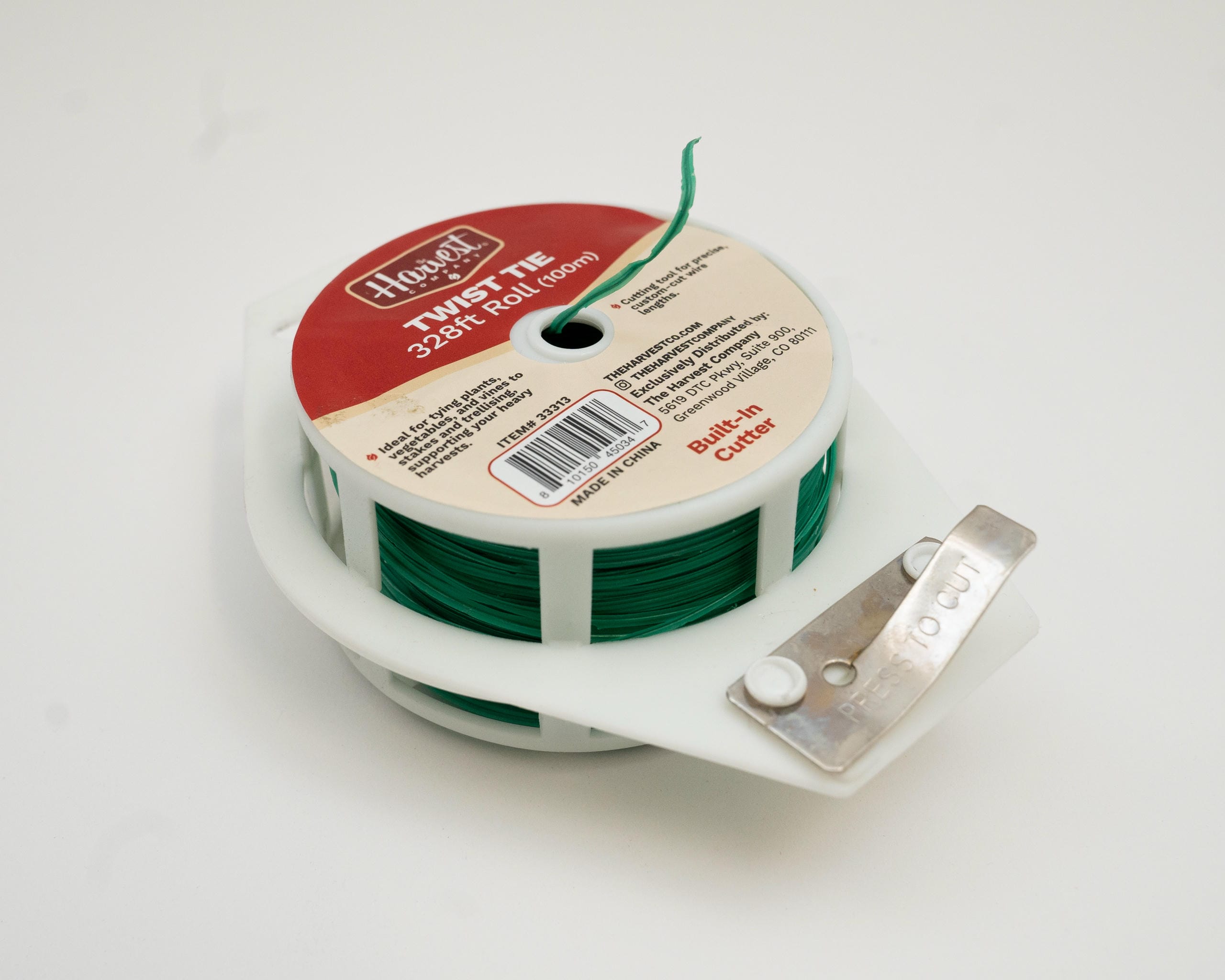 Spool of green twine with a cutter on a white background